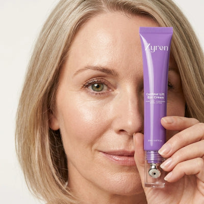 Woman holding a Zyren Contour Lift Eye Cream tube in front of one eye