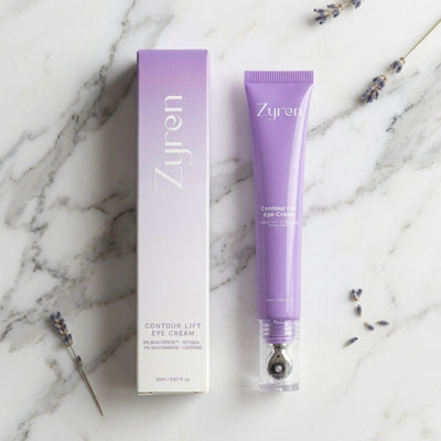 Zyren Contour Lift Eye Cream tube and lilac box on white marble with sprigs of lavender